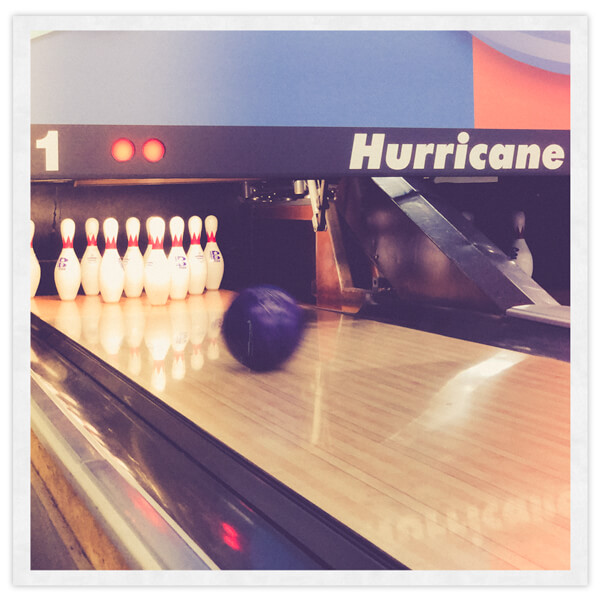 A bowling ball rolling toward bowling pins